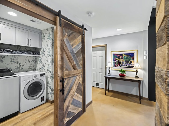 washroom featuring cabinet space, a barn door, visible vents, baseboards, and independent washer and dryer