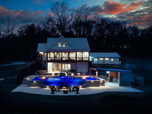 rear view of house with a patio area, an outdoor pool, a balcony, and an in ground hot tub