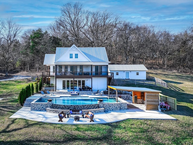 back of property with a balcony, a patio area, metal roof, and a yard