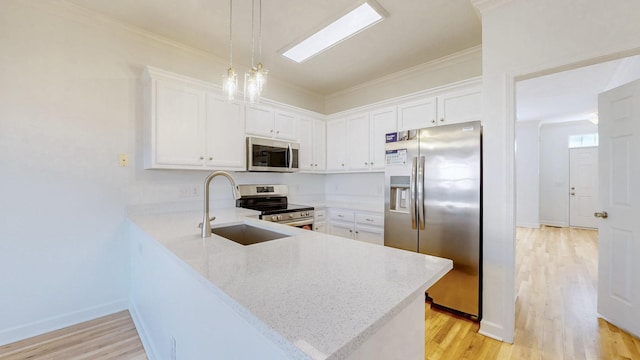 kitchen with a sink, stainless steel appliances, a peninsula, and ornamental molding