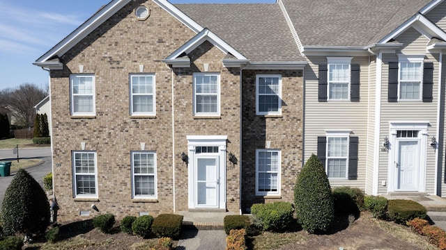 view of front facade featuring crawl space, brick siding, and roof with shingles