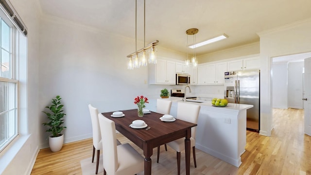 dining space with baseboards, crown molding, and light wood-style floors