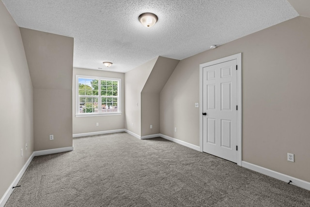 bonus room featuring carpet floors, vaulted ceiling, a textured ceiling, and baseboards