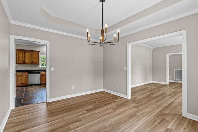 empty room featuring wood finished floors, a raised ceiling, visible vents, and baseboards