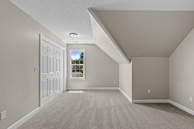 additional living space featuring carpet, baseboards, vaulted ceiling, and a textured ceiling