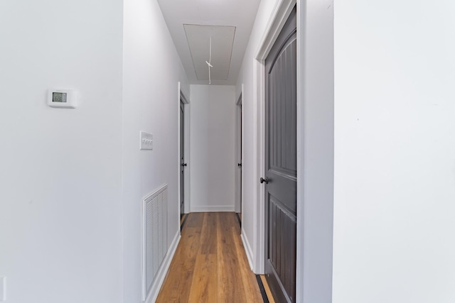 corridor with visible vents, light wood-type flooring, attic access, and baseboards