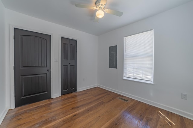 unfurnished bedroom featuring baseboards, dark wood finished floors, visible vents, and electric panel