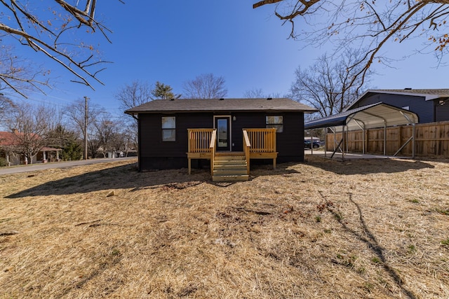 rear view of property featuring a detached carport, fence, and a deck