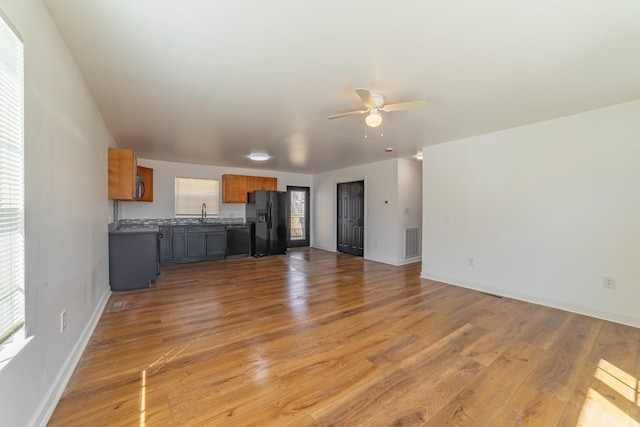 unfurnished living room with plenty of natural light, light wood-style floors, ceiling fan, and visible vents