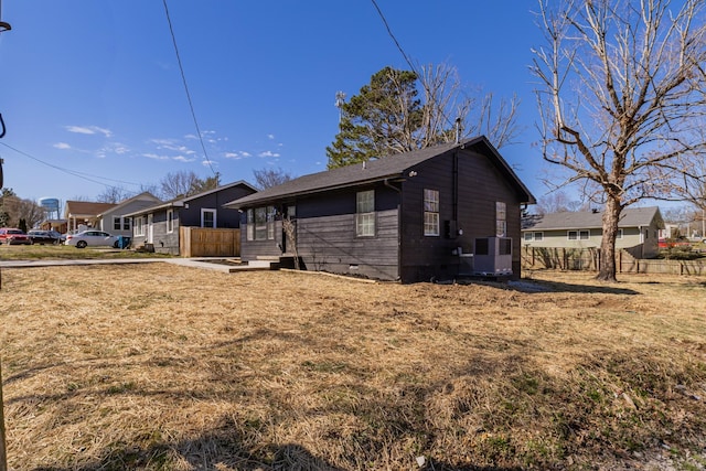 view of side of property featuring central air condition unit, a residential view, fence, and a yard