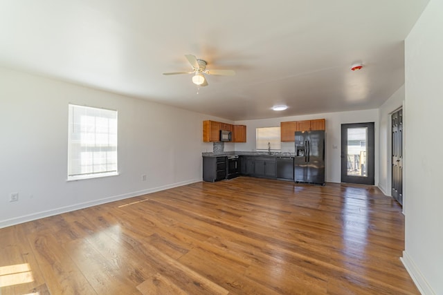 unfurnished living room featuring dark wood-type flooring, ceiling fan, and baseboards