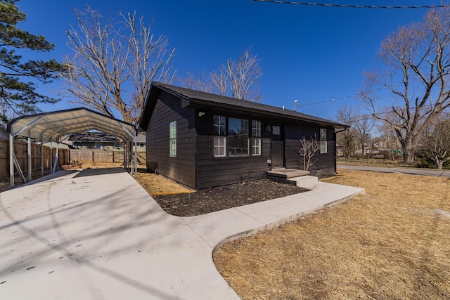 view of front facade featuring driveway, fence, and a carport