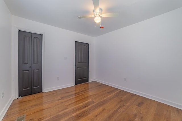 unfurnished bedroom featuring a closet, visible vents, baseboards, and wood finished floors