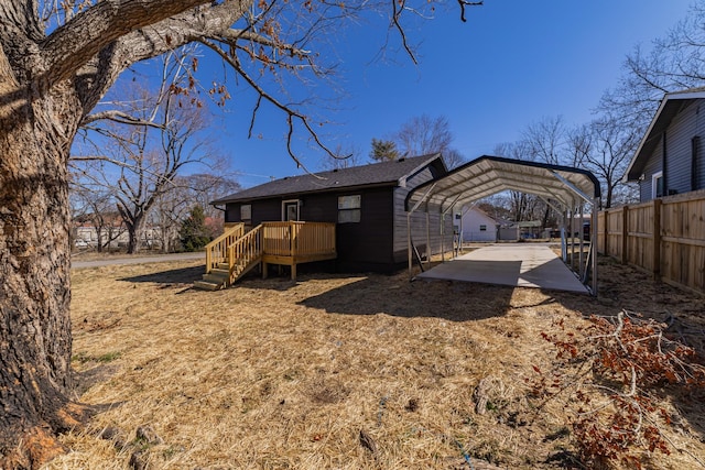 rear view of house featuring a carport, fence, a deck, and dirt driveway