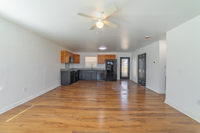 kitchen with light wood-style floors, baseboards, brown cabinets, and black appliances