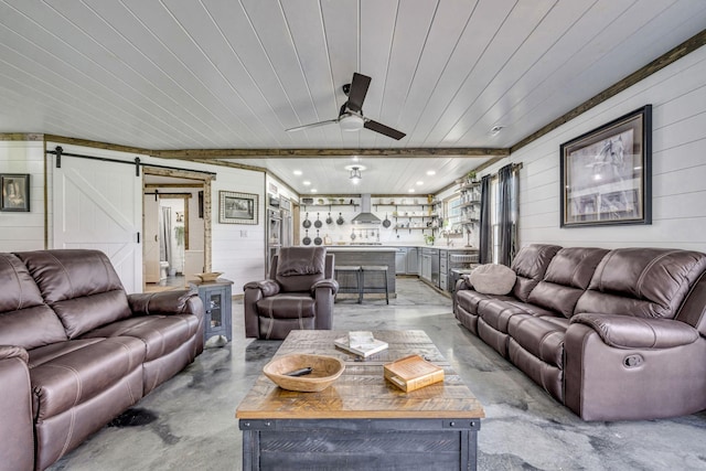 living room with concrete flooring, a barn door, wooden walls, wood ceiling, and a ceiling fan