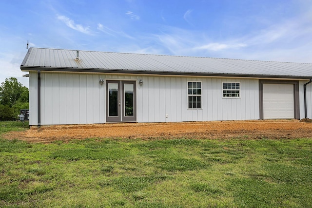 back of property with a yard, french doors, metal roof, and a garage