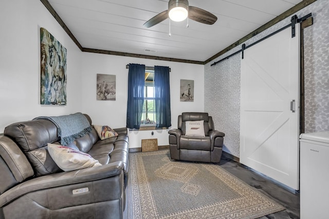 living room with ceiling fan, a barn door, visible vents, baseboards, and ornamental molding