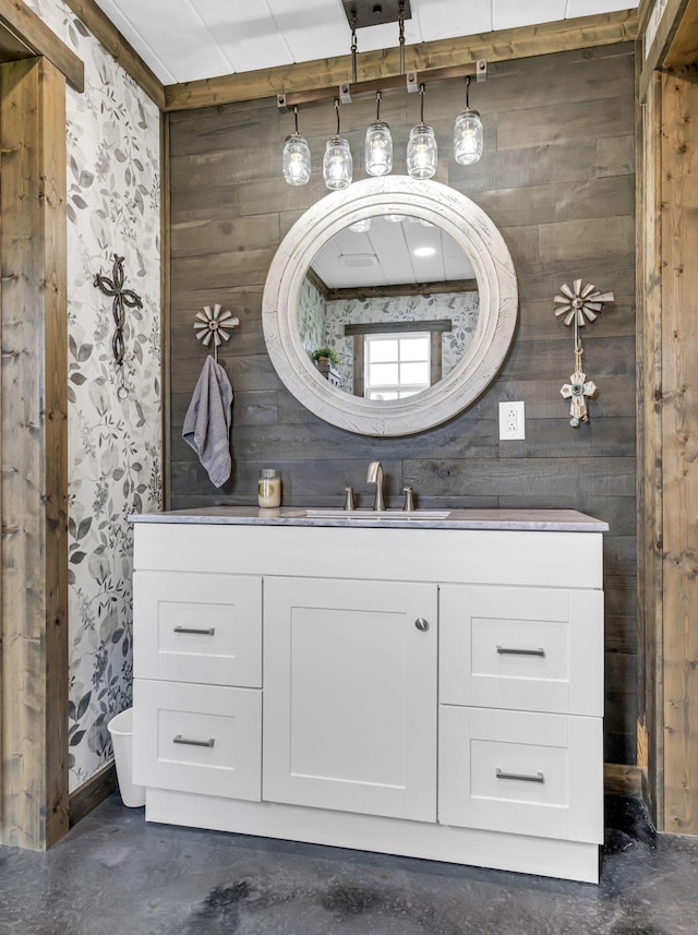 bathroom with wooden walls, concrete floors, and vanity