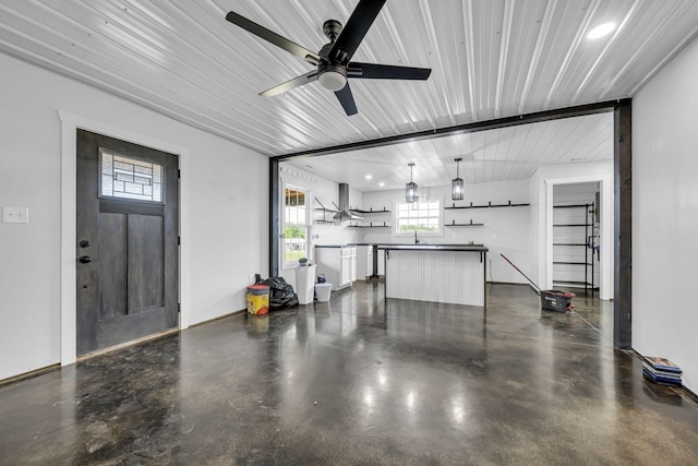 garage with ceiling fan, a sink, and baseboards