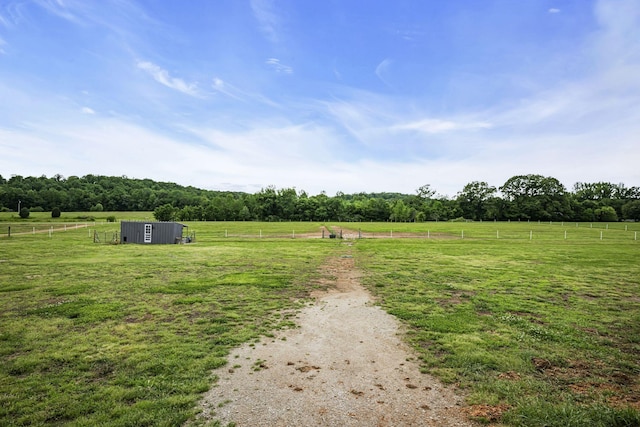 view of yard featuring an outbuilding, a rural view, and fence