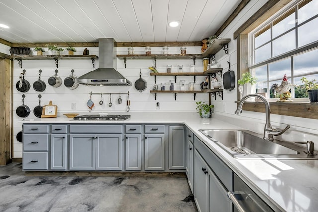 kitchen featuring gray cabinetry, a sink, wall chimney range hood, open shelves, and stainless steel gas stovetop