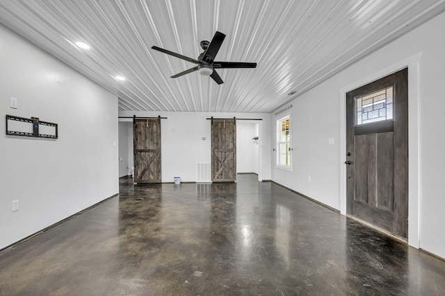 unfurnished living room with finished concrete floors, visible vents, ceiling fan, and a barn door