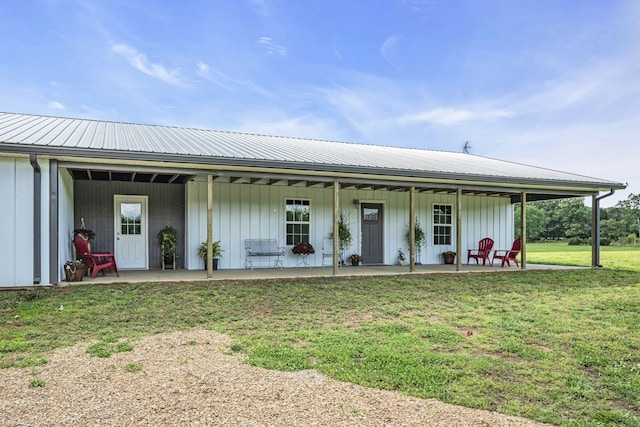 view of front facade with board and batten siding, metal roof, and a front lawn