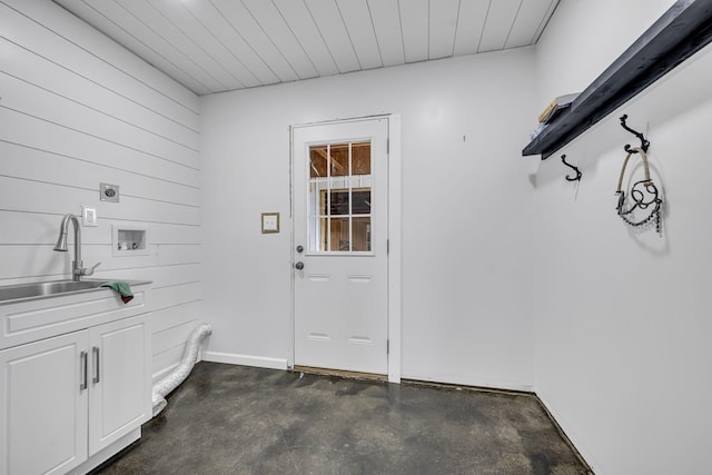 doorway to outside featuring concrete floors, a sink, and baseboards