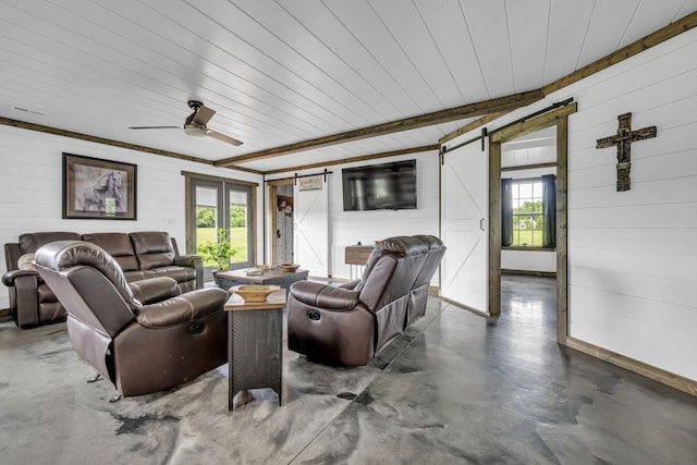 living room featuring a barn door, a ceiling fan, and concrete flooring