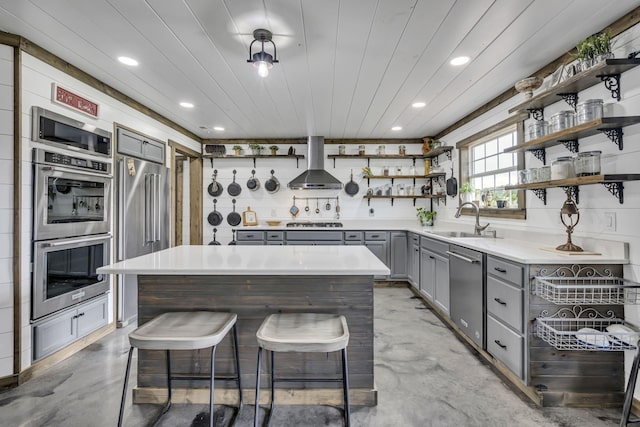 kitchen featuring open shelves, gray cabinetry, finished concrete floors, a sink, and wall chimney exhaust hood