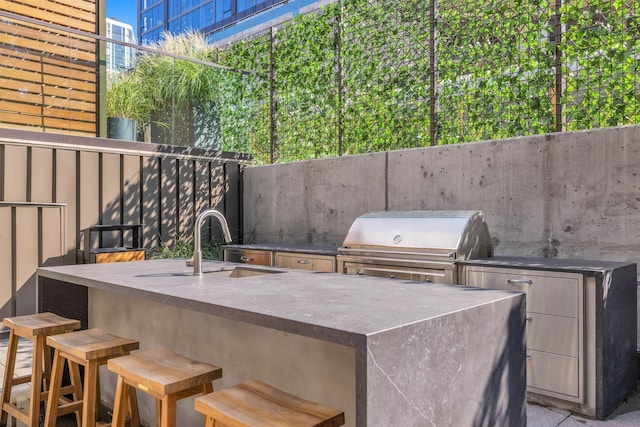 view of patio featuring outdoor wet bar, area for grilling, a sink, fence, and exterior kitchen