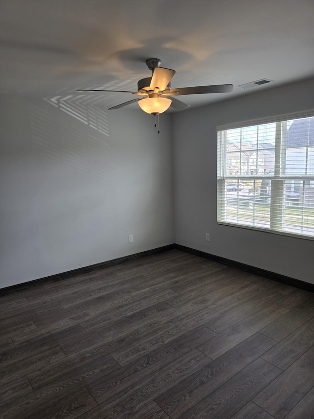 spare room featuring dark wood-style floors, baseboards, visible vents, and a ceiling fan