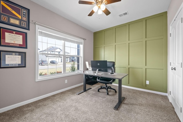 home office featuring a decorative wall, carpet floors, a ceiling fan, baseboards, and visible vents