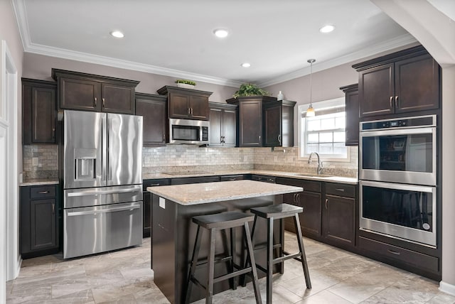 kitchen featuring a kitchen island, stainless steel appliances, dark brown cabinets, crown molding, and a sink