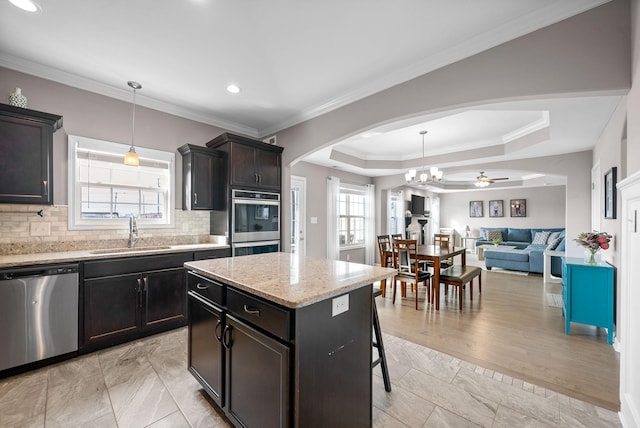 kitchen with arched walkways, decorative backsplash, appliances with stainless steel finishes, a breakfast bar, and a sink