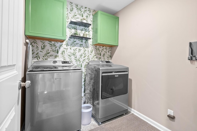 laundry room featuring washing machine and dryer, cabinet space, baseboards, and wallpapered walls