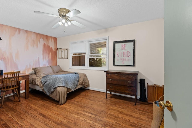 bedroom with ceiling fan, a textured ceiling, baseboards, and wood finished floors