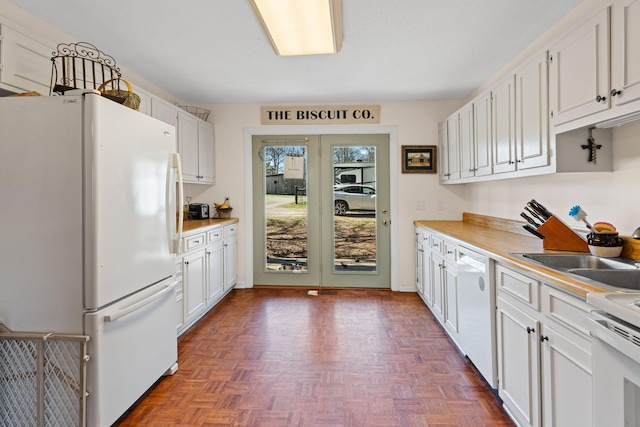 kitchen featuring light countertops, white appliances, a sink, and white cabinets