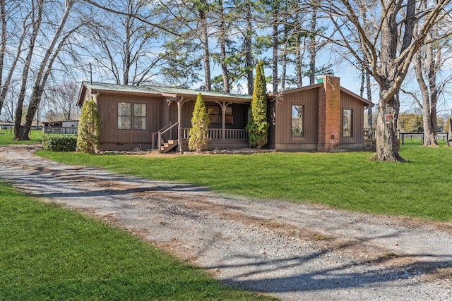 view of front of property featuring driveway, a chimney, crawl space, covered porch, and a front lawn