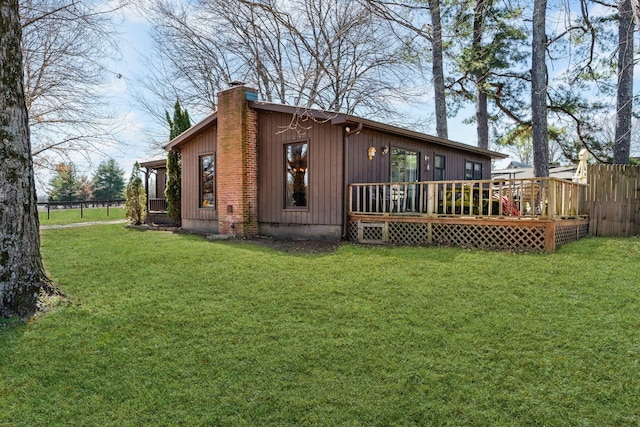 exterior space with a chimney, fence, a deck, and a yard