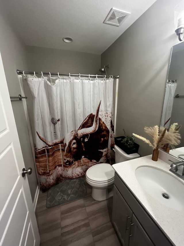 bathroom featuring toilet, visible vents, a shower with shower curtain, and vanity