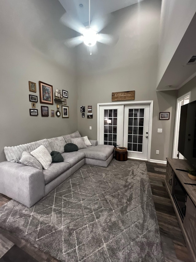 living room with visible vents, a towering ceiling, dark wood-type flooring, a ceiling fan, and baseboards