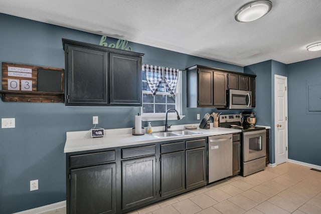 kitchen featuring light tile patterned flooring, stainless steel appliances, a sink, baseboards, and light countertops