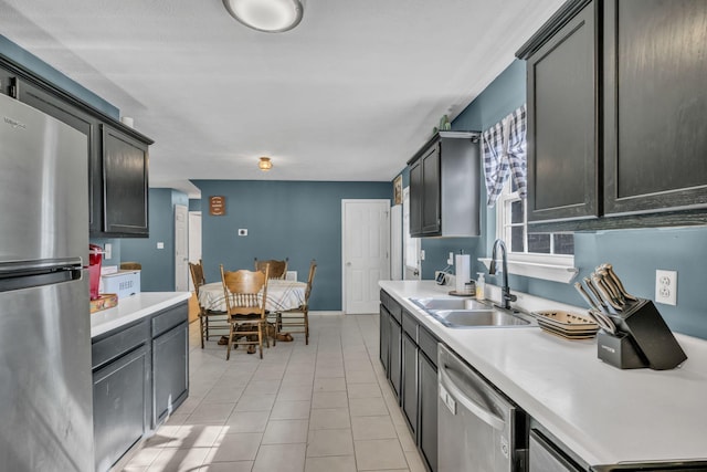 kitchen featuring light tile patterned flooring, stainless steel appliances, a sink, and light countertops