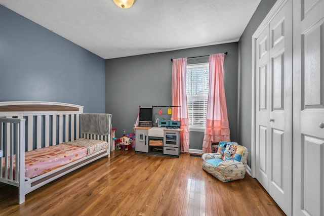 bedroom featuring a nursery area and wood-type flooring