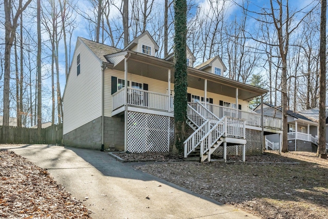 view of front of property featuring covered porch, stairs, and fence