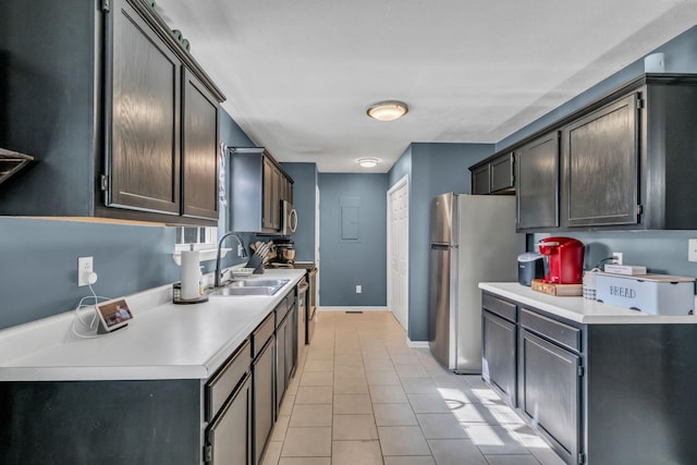 kitchen with stainless steel appliances, light countertops, a sink, and light tile patterned flooring