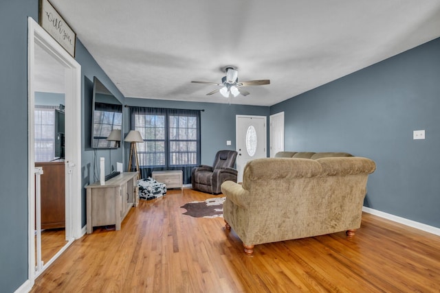 living area with light wood-style floors, baseboards, and a ceiling fan