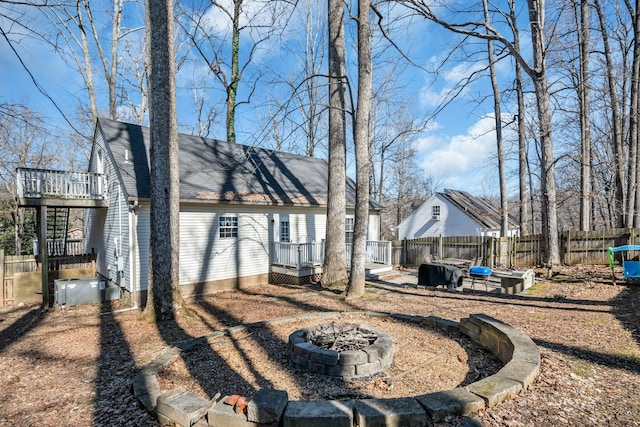 rear view of house with an outdoor fire pit, roof with shingles, fence, and a wooden deck